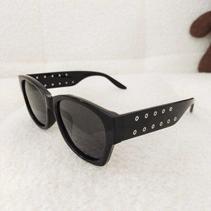 Close-up of black oversized kids sunglasses with silver rivets on the temples over soft fabric
