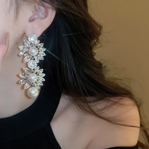 Close-up of dangling flower earrings with pearls and crystals on a model's ear