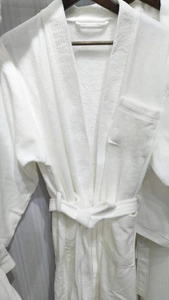 Close-up of thick white cotton hotel bathrobe featuring embroidered blue Days Hotel logo