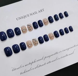 Détail de faux ongles bleu foncé et rose avec motifs de lignes et strass