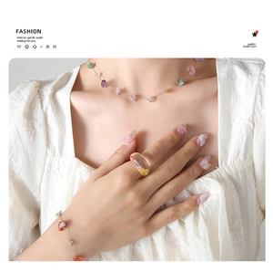 Detail of colorful natural stone necklace set and resin ring with dried flower on model