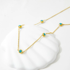 Golden stainless steel necklace with blue devil eye beads on a white shell prop