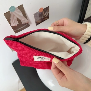Detail showing red corduroy pouch with white lining and zip closure for storage