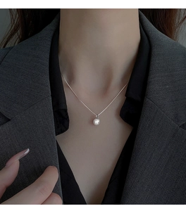 Close-up of a high-luster pearl pendant necklace on a model with a minimalist silver chain