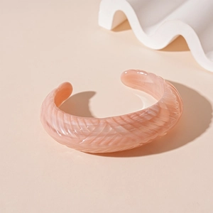 Detail of pink resin cuff bracelet featuring intricate 3D embossed feather textures
