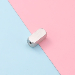 Macro detail of silver rectangular stainless steel charm with brushed metal texture