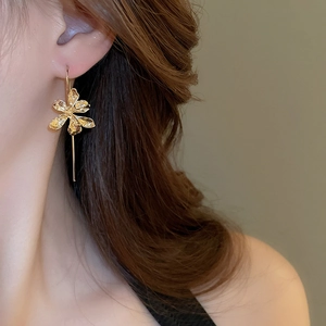 Detailed close-up of golden iris flower earring with elegant long metal fringe on model