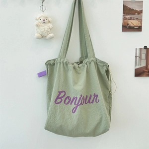 Detail of light green waffle textured nylon drawstring tote bag with purple Bonjour print