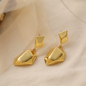 Macro detail of 18K gold plated heart earrings on soft beige silk background texture
