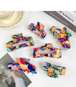 Detailed view of six floral pattern hair claw clips set against lifestyle props