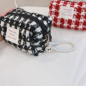 Close-up of tweed makeup bags with pearl handles and decorative fabric labels