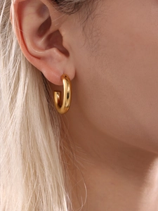 Close-up of chunky gold C-shaped earrings with 18k PVD plating on female model