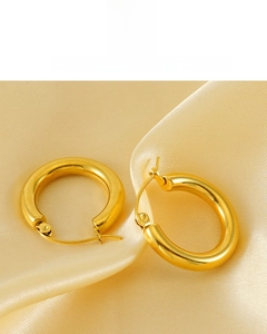 Detail of 18K vacuum plated golden hoop earrings showing glossy mirror finish on silk