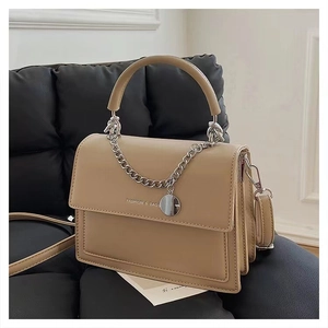 Detail of beige PU leather shoulder bag with chain and Fashion & Bags text on a sofa