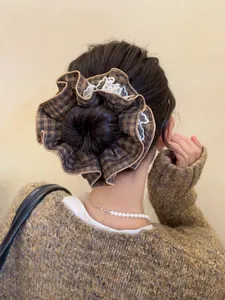 Detail of a large brown plaid scrunchie with lace edges worn on a bun hairstyle
