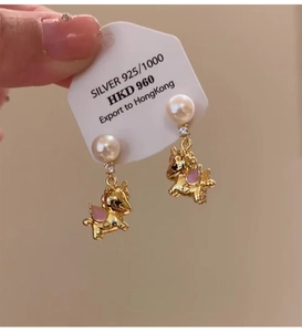 Macro detail of gold-plated unicorn earrings with pearls on a 925 silver stud