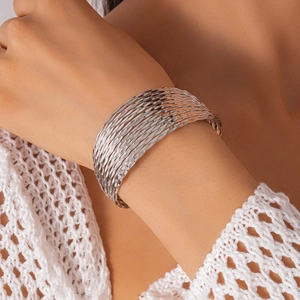 Silver multi-layer geometric cuff bracelet styled on wrist with knitwear detail