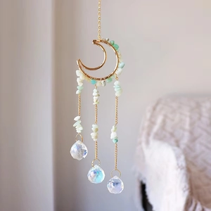 Detailed view of moon shaped suncatcher with hand-wrapped green stones and crystal prisms