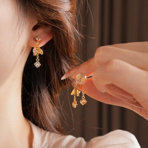 Detail of flower tassel earring with gold plating and clear clip-on back on ear