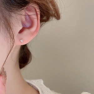 Gros plan d'une boucle d'oreille cœur en or minimaliste avec un zircon