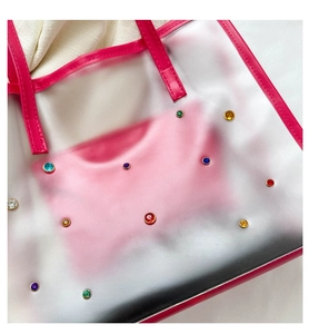 Detail of colorful rhinestones on translucent pink PVC tote bag with leather trim