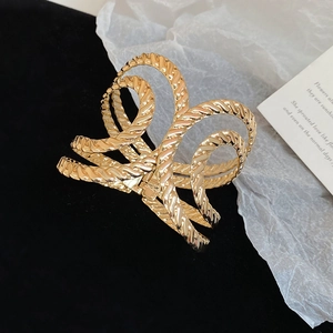Macro shot of large golden metal hair claw clip with unique twisted texture and glossy finish