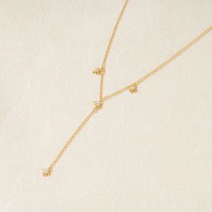 Detail of gold S925 silver Y-shaped tassel necklace with four sparkling star pendants