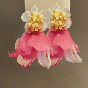 Detailed macro view of delicate pink fabric flower earrings with yellow stamen accents