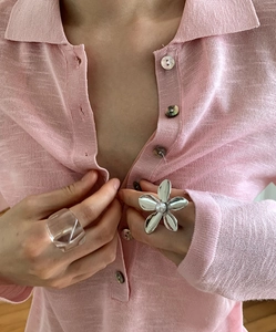 Detail of silver flower ring with white pearl center and a transparent resin ring on hand
