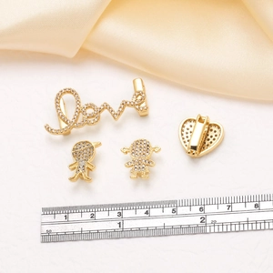 Makro-Detail von 18k vergoldeten Herz- und 'Love'-Anhängern mit Mikro-Pave-Zirkon-Kristallen