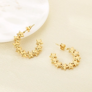 Elegant gold stainless steel star-shaped hoop earrings on beige textured fabric