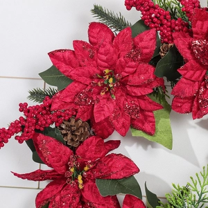 Christmas wreath with red poinsettia, shiny berries, and natural pine cones on green needles