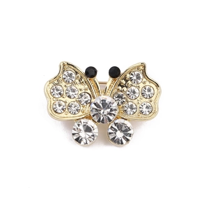 Macro detail of gold butterfly brooch with clear crystals and black rhinestone antennae