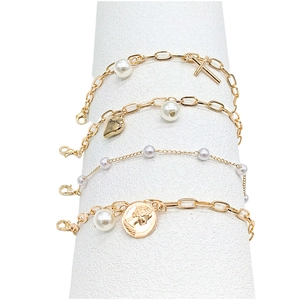 Detail of four-piece gold bracelet set with pearls, crosses, hearts, and coin charms