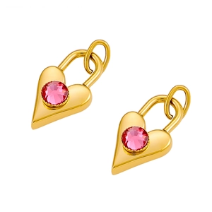 Detail of golden heart stud earrings featuring a round pink zircon center and polished finish