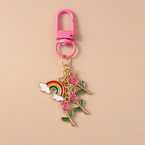 Detail of pink enamel rose flowers and rainbow charms on a luxury metal keychain