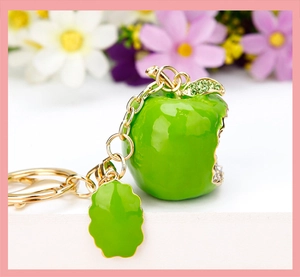 Macro shot of green apple keychain with enamel coating and sparkling rhinestones