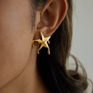 Detailed view of gold molten star earring with liquid metal drip texture on model