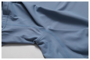Détail macro des coutures renforcées sur le tissu bleu clair du body de yoga