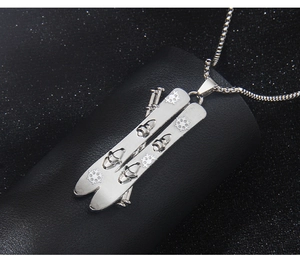 Detailed close-up of a silver stainless steel snowboard and ski pole pendant necklace
