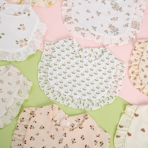 Detail view of cotton muslin baby bibs featuring ruffle edges and floral tulip patterns