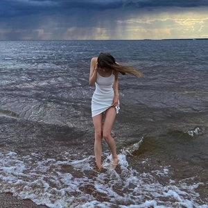 Slim fit white summer mini dress with spaghetti straps on a scenic beach background