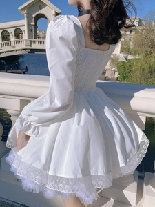 Detalle de vestido blanco con mangas abullonadas, espalda fruncida y borde de encaje