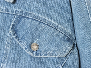 Nahaufnahme der Jeansjacke mit metallischen Sterngravur-Knöpfen und feinen Nähten