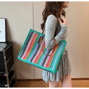 Detail view of large striped woven tote bag with brown handles on model shoulder