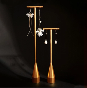 Detail of white petal earrings and pearl drops on a luxury gold metal jewelry stand