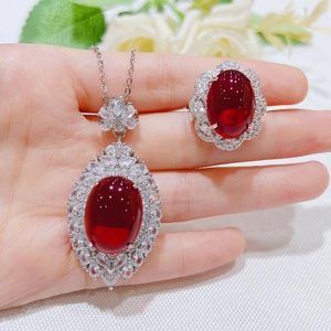 Macro shot of oval pigeon blood red ruby ring and matching pendant set on model