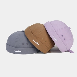 Three embroidered brimless docker caps in grey, brown, and lilac with small fish logo