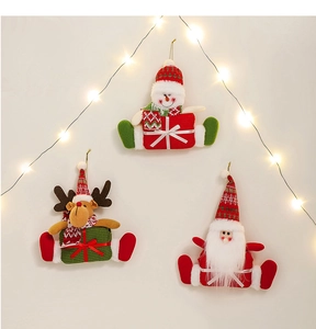 Hanging plush Christmas ornaments with Santa, snowman and deer on a warm festive background