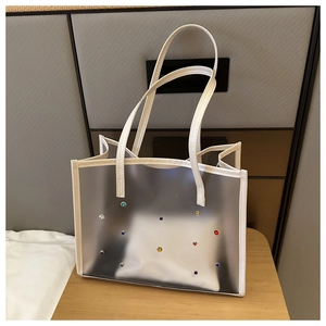 Detail of frosted PVC tote bag with white leather trim and colorful rhinestone studs